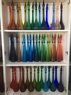 a shelf filled with lots of colorful vases sitting on top of it's shelves