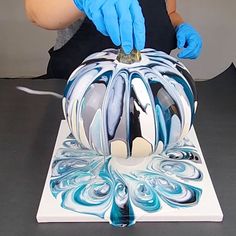 a person in blue gloves is working on a bicycle helmet with an acrylic paint job