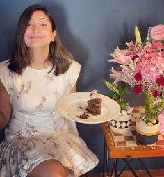 a woman holding a plate with a piece of cake on it