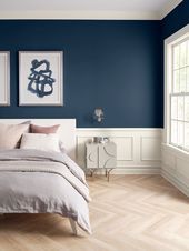 a bedroom painted in blue and white with wood flooring, two paintings on the wall