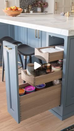 an open drawer in the middle of a kitchen with stools and bowls on it