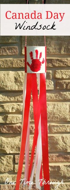 the canadian flag made out of ribbon hanging from a brick wall with text overlay that reads canada day windsock