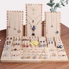 an assortment of jewelry is displayed on a wooden stand with flowers in the vase behind it