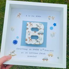 a person holding up a white frame with the letter b in it and animals on it