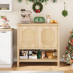 a small christmas tree is next to a wooden cabinet with ornaments on it and a coffee maker