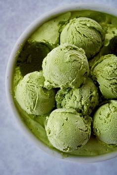 a bowl filled with green ice cream on top of a table