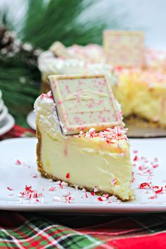 a slice of cheesecake with sprinkles on a white plate next to a christmas tree