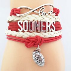 a red and white bracelet with a football charm on it that says, love someone