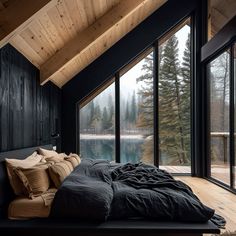 a large bed sitting under a window next to a wooden floor covered in pillows and blankets