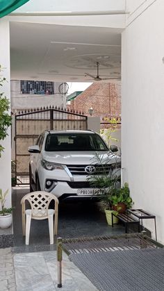 a car parked in front of a house with a white chair and green awning