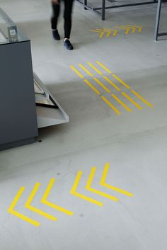 two people are walking through an airport with yellow arrows on the floor