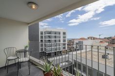 an apartment balcony with chairs, table and potted plants