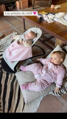 two babies laying on top of pillows in front of a table with a zebra print rug