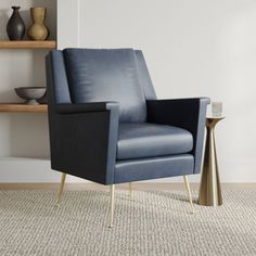 a blue leather chair sitting on top of a rug next to a table with vases