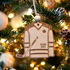 a wooden ornament hanging from a christmas tree with hockey jersey and puck on it