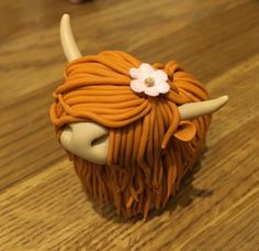 an animal head made out of yarn on top of a wooden table with a flower in it's hair