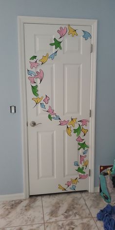 a door with birds painted on it in a blue room next to a teddy bear