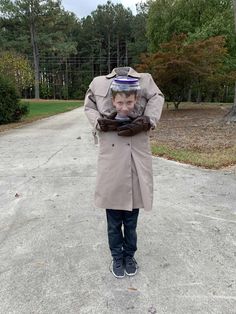 a man in a trench coat is covering his face with gloves