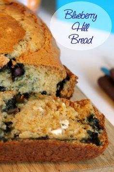 a loaf of blueberry almond bread sitting on top of a wooden cutting board next to some chocolate chips