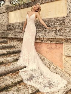 a woman in a wedding dress leaning against a stone wall with her hand on the side