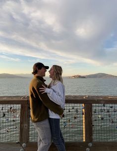 a man and woman standing next to each other near the ocean