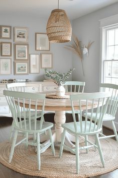 a dining room table with four chairs and pictures on the wall above it, along with a round rug