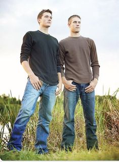 two men standing next to each other in the grass