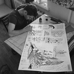 a man sitting at a table working on a drawing