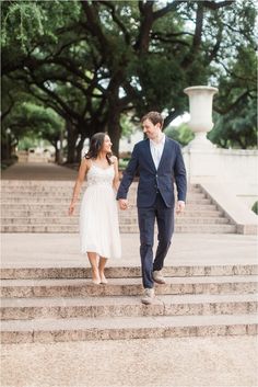 a man and woman walking up some steps together in front of the stairs are trees