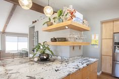 a kitchen with marble counter tops and wooden cabinets, along with hanging lights above the sink