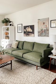 a living room with green couches and pictures on the wall above it's coffee table