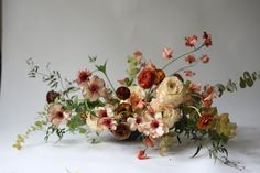 a vase filled with lots of flowers on top of a white tablecloth covered floor