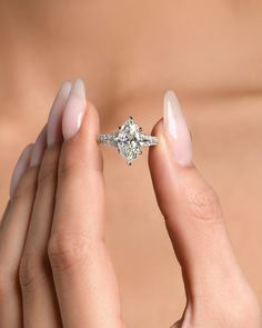 a woman's hands holding an engagement ring in front of her face and the other hand