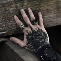 a person's hand with tattoos and rings on it