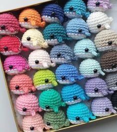 a box filled with lots of small crocheted little whale toy figures in different colors