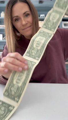 a woman sitting at a table with money in front of her and holding it up to the camera