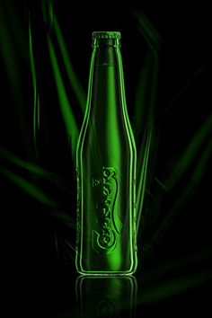 a green beer bottle sitting on top of a black table next to a dark background