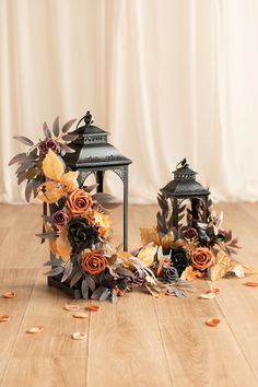 two black lanterns with flowers and leaves on the floor