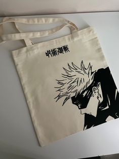 a tote bag with an anime character drawn on the front and side, sitting on top of a table