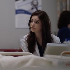 a woman sitting in a hospital bed looking at her laptop