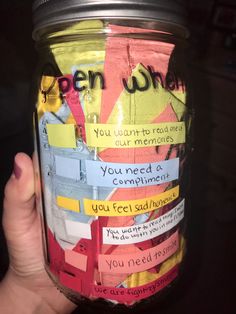 a person holding up a jar filled with paper and magnets that read open where you need a compliment