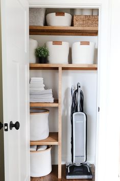 the closet is organized with white containers and black ironing board