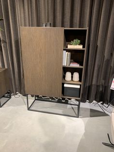 a room with a bookcase and other items on display in front of a curtained wall