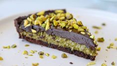 a piece of chocolate cake with pistachios on it sitting on a plate