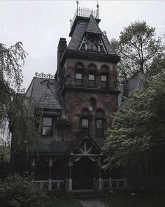 an old house with a steeple and clock tower on the top floor, surrounded by trees