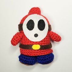 a crocheted red and blue stuffed animal with black eyes on it's face