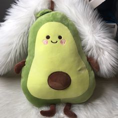 a stuffed avocado sitting on top of a white furry surface with its eyes closed