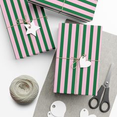 three wrapped gift boxes sitting on top of a table next to scissors and twine