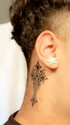 a close up of a person with a cross tattoo on their neck and behind the ear