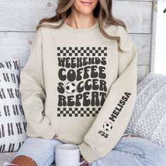 Stay cozy and stylish on the sidelines with our personalized soccer mom crewneck sweatshirt! The front features a retro-inspired "weekends, coffee, soccer, repeat" text, perfect for every soccer mom out there. On the left sleeve, you'll find a design showcasing your kid's name and their jersey number, adding a special touch to this already unique piece. Whether you're cheering on your little star or running errands, this sweatshirt is a must-have for any soccer mom who wants to show off their pr White Long Sleeve Sweatshirt For Weekend, Crew Neck Sweatshirt For Weekend, Weekend White Crew Neck Sweatshirt, White Crew Neck Sweatshirt For Weekend, Long Sleeve Graphic Print Sweatshirt For Weekend, Graphic Print Long Sleeve Sweatshirt For Weekend, Sporty Graphic Print Sweatshirt For Weekend, Weekend Relaxed Fit Sweatshirt With Letter Print, Weekend Letter Print Relaxed Fit Sweatshirt